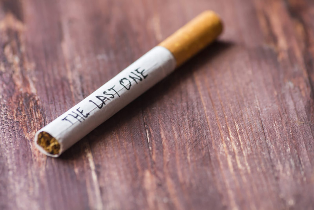 A closeup phot of a wooden table with a cigarette with the words, "the last one" written on the side.
