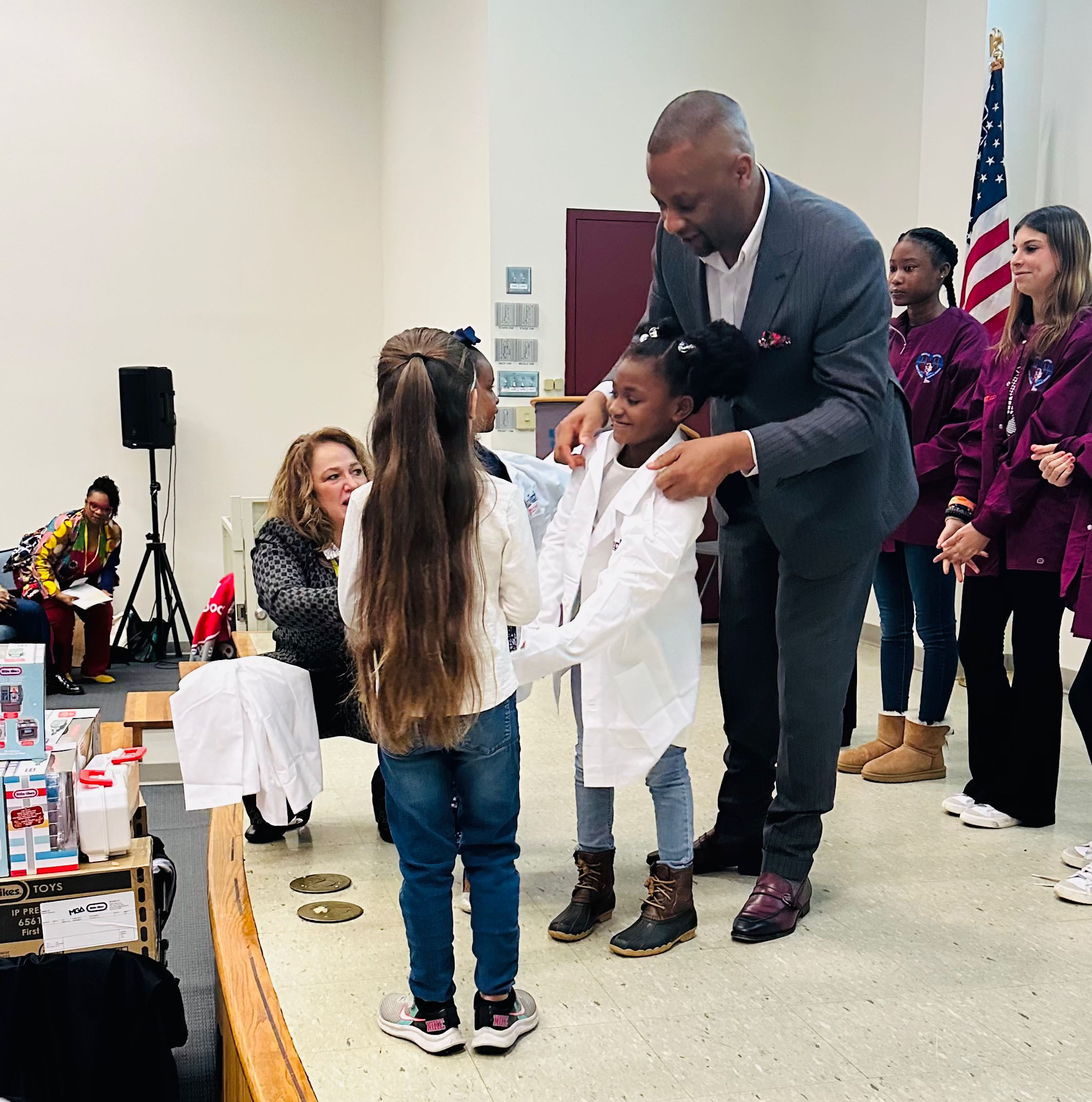 Dr. Bizzell helping present lab coats