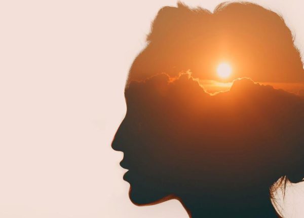 side view of a person's head with a sunset image in it
