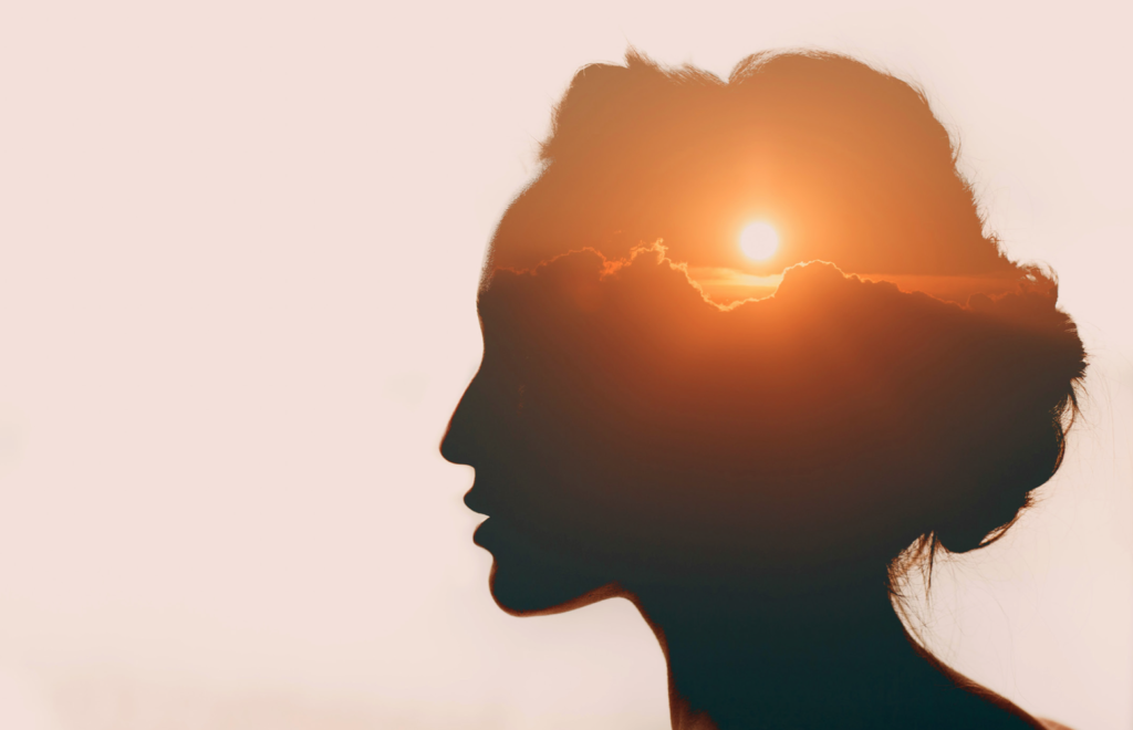 side view of a person's head with a sunset image in it